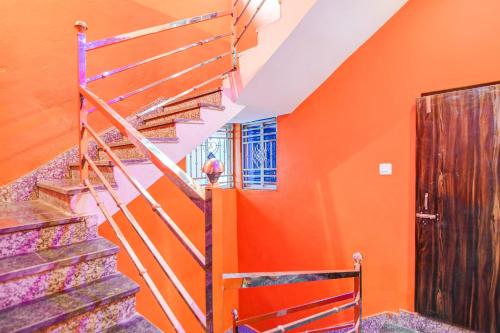 a staircase in a house with an orange wall at Hotel O Elegant Stay CDA in Cuttack