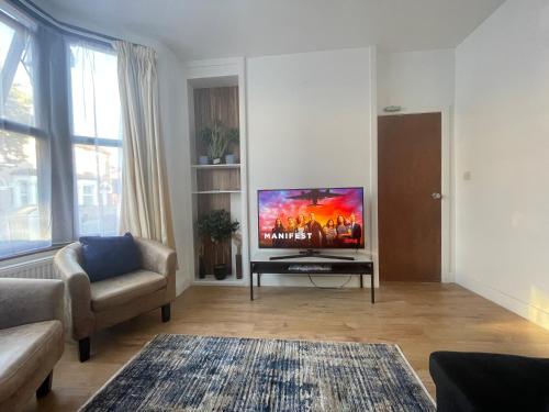 a living room with a large flat screen tv at beautifull house with 6 double bedrooms in London