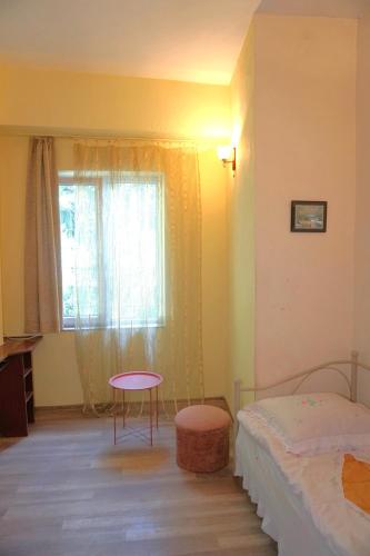 a bedroom with a bed and a table and a window at Pospolita Guest House in Kutaisi