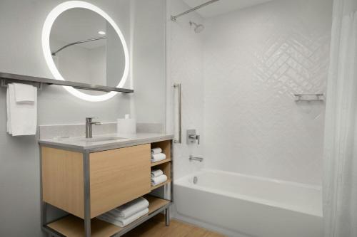 a bathroom with a sink and a tub and a mirror at TownePlace Suites by Marriott Jacksonville Mayport in Jacksonville