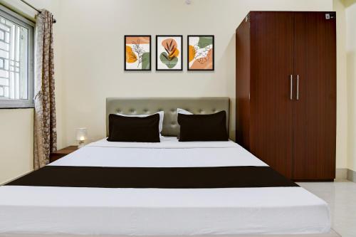 a bedroom with a large white bed with black pillows at Super HOTEL O GATHABANDHAN in Dhanbād