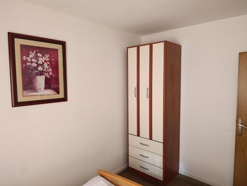 a bedroom with a cabinet and a painting on the wall at Apartman Dali in Blagaj