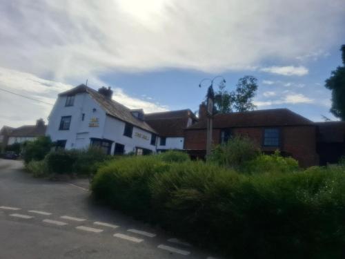 a white house and a red brick building at Hill Top Hideaway Shepherds Hut with Hot Tub in Woodham Mortimer