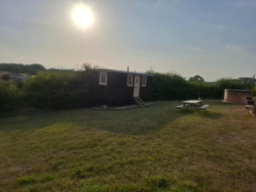 a small house with a picnic table in a yard at Hill Top Hideaway Shepherds Hut with Hot Tub in Woodham Mortimer