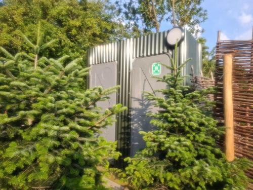 a metal utility box in a garden with two trees at Hill Top Hideaway Shepherds Hut with Hot Tub in Woodham Mortimer