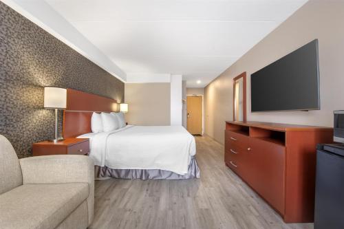 a hotel room with a bed and a flat screen tv at Best Western Hotel Brossard in Brossard