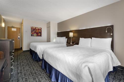 a hotel room with two beds and a television at Best Western Hotel Brossard in Brossard