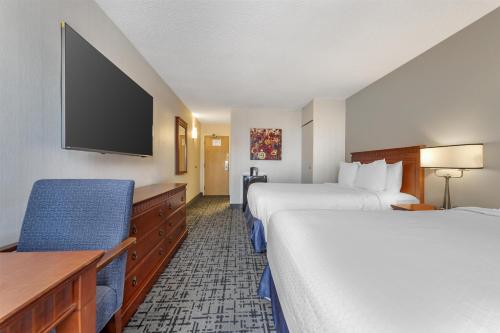 a hotel room with two beds and a flat screen tv at Best Western Hotel Brossard in Brossard
