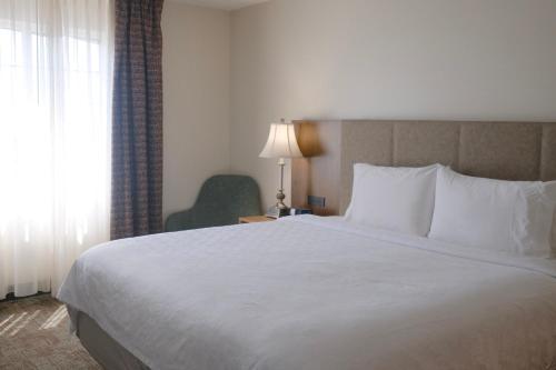 a bedroom with a large white bed and a chair at Staybridge Suites Austin Airport by IHG in Austin