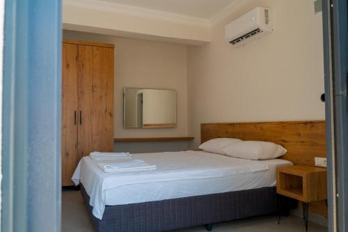 a bedroom with a bed with white sheets and a mirror at Güneş Boutique Hotel - Oludeniz in Oludeniz