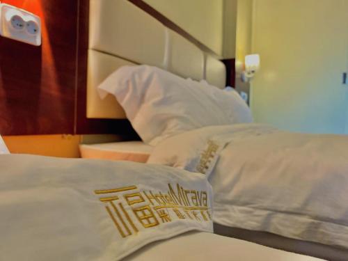 a bed with white sheets and pillows in a room at Hotel Mirava in Maputo