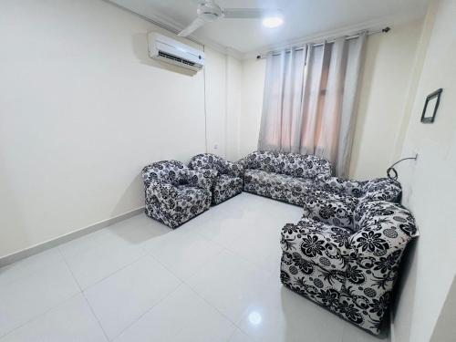 two chairs sitting in a room with white tiles at العربي للشقق المفروشة in Salalah