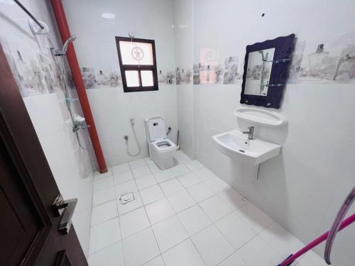 a white bathroom with a toilet and a sink at العربي للشقق المفروشة in Salalah