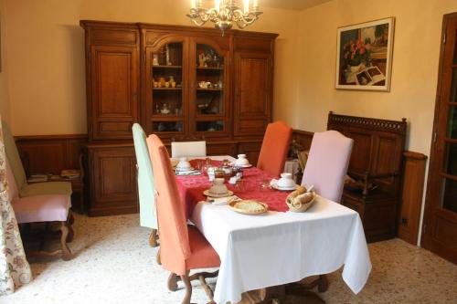 un comedor con una mesa con sillas y una lámpara de araña en La Maison du Verger, en Acquigny