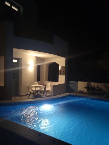 a swimming pool at night with a table and chairs at Located by the sea one beachfront Private Captain Lazaros Pool Villa with loft in 750sqm spacious private plot-Jacuzzi-sunrelax-furnished terace-gazebo-private parking,sleep 3 adults and 2 children, just steps from the Black Beach-Seaview in Perissa
