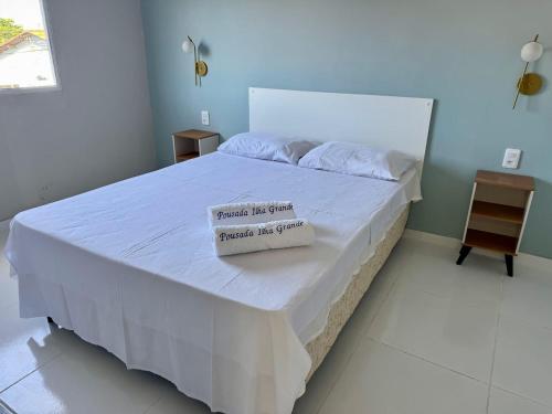 a bedroom with a white bed with a sign on it at Pousada Ilha grande in Morro da Marinha