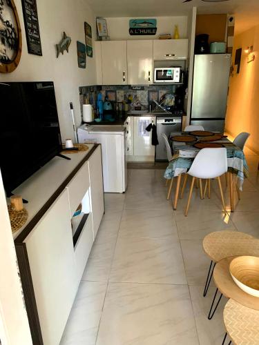 une cuisine avec des armoires blanches et une table et des chaises dans l'établissement Cap d'Agde méditerranée studio 4 pers piscine rdc parking gratuit, au Cap d'Agde