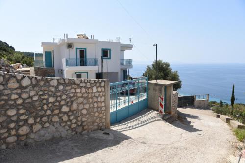 a house on a hill with a stone wall at Endless blue Apartments in Dhërmi