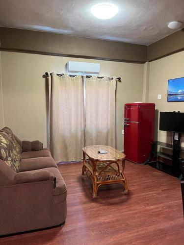 a living room with a couch and a table and a red refrigerator at Enjoy Hotel in Caye Caulker
