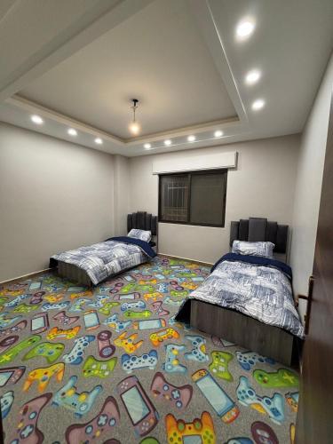 two beds in a room with a large rug at شقة واسعة مع ترس كبير in Amman