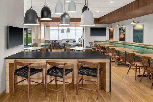 a restaurant with tables and chairs and a bar at Fairfield by Marriott Inn & Suites Norwalk Des Moines in Norwalk