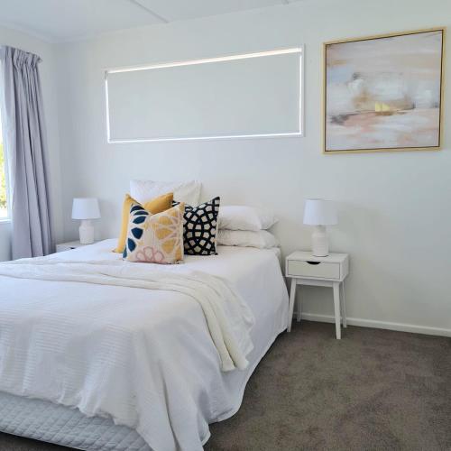 a white bedroom with a bed with pillows on it at Sea View Oamaru in Oamaru