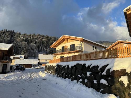 a house in the snow with a stone wall at Obermöschach 10A in Obermöschach