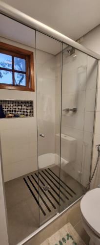 a glass shower in a bathroom with a toilet at Pousada Chalé Poder das Pedras in Sao Paulo