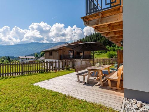 a wooden patio with a table and an umbrella at Obermöschach 10B in Obermöschach