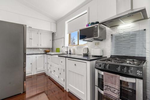 a kitchen with white cabinets and a stove top oven at Incredible Location 2 Bed CBD Dream in Orange