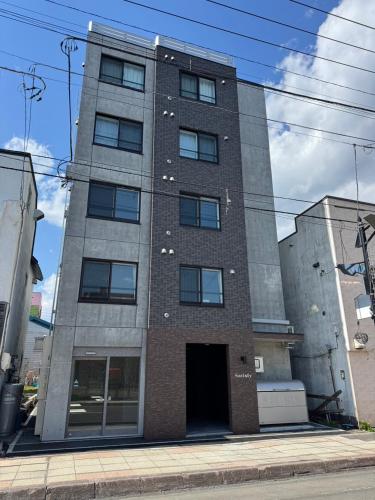 a tall brick building with a door on a street at Stisfy サティスファイ in Chitose