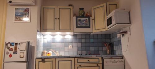 Elle comprend une petite cuisine avec des placards blancs et un réfrigérateur. dans l'établissement AU NAUTILUS studio au port avec loggia et parking - plage à 50 m, à Saint-Cyprien