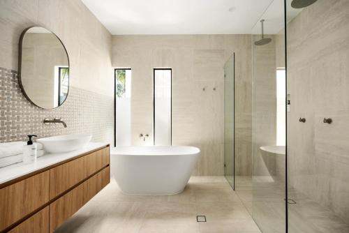 un bagno con vasca, lavandino e specchio di Casa Six on Witta a Noosa Heads