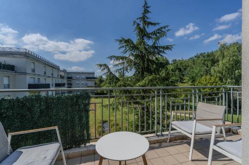 d'un balcon avec des chaises blanches et un arbre. dans l'établissement Appartement central 6 personnes à 10 minutes de Disneyland, à Montévrain