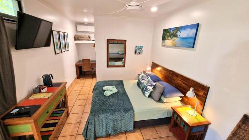 a small living room with a couch and a tv at Rainforest Motel in Mission Beach