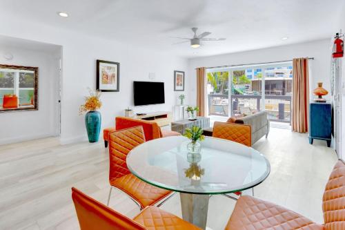 a living room with a glass table and orange chairs at Orange Dream on the Water in Fort Lauderdale