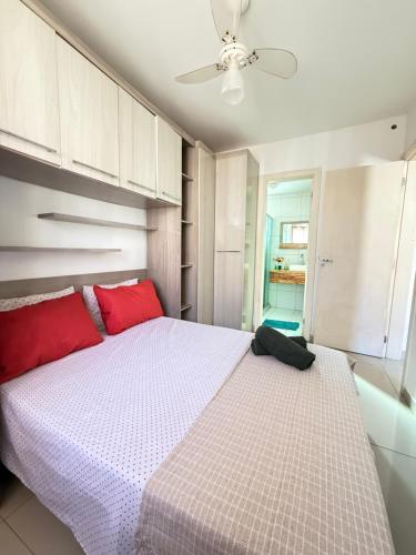 a bedroom with a large bed with red pillows at Apartamento 100 metros da praia com piscina in Ilhéus