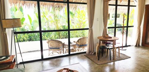a living room with a large glass door with chairs and a table at Villa Pura Vida Apartments Siargao in General Luna
