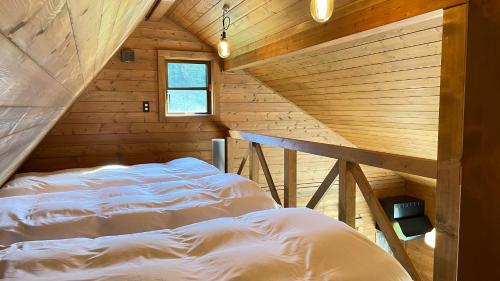 ein Schlafzimmer mit einem Bett in einem Holzzimmer in der Unterkunft Log-inn 一棟貸しログハウス in Ama