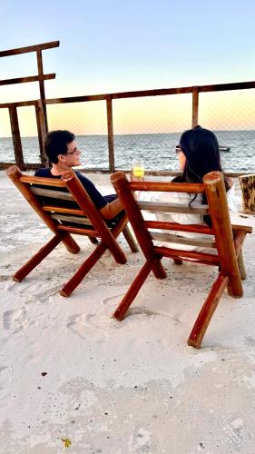 two people sitting on a bench on the beach at Casa de Praia Tutóia in Tutóia