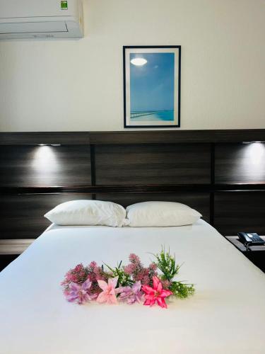 a white bed with flowers on top of it at Hotel Le Paris in Noumea