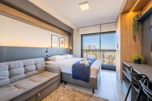 a bedroom with a bed and a couch and a window at Skyline Parque Moinhos by LikeHome in Floresta