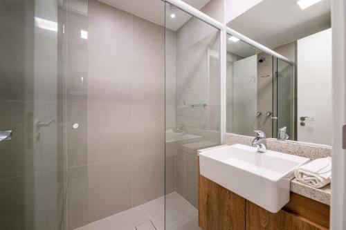 a white bathroom with a sink and a shower at Skyline Parque Moinhos by LikeHome in Floresta