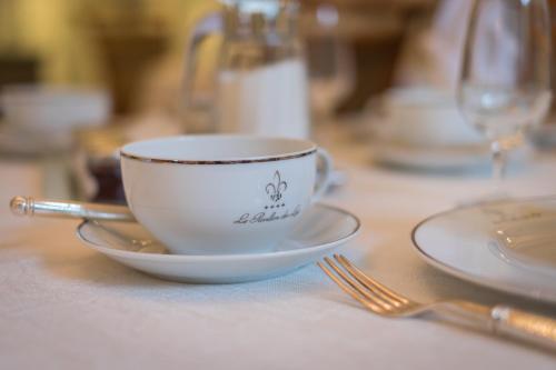 a cup and saucer on a table with a fork at Le Pavillon des Lys - Hôtel Particulier in Amboise