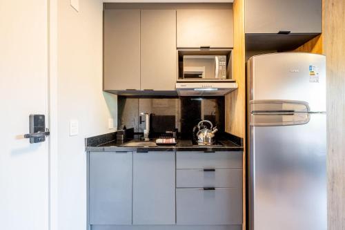 a kitchen with white cabinets and a refrigerator at Skyline Parque Moinhos by LikeHome in Floresta