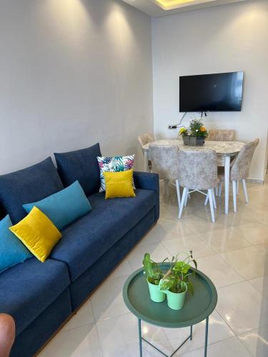 Una sala de estar con un sofá azul y una mesa. en Miramar del mar, en Martil