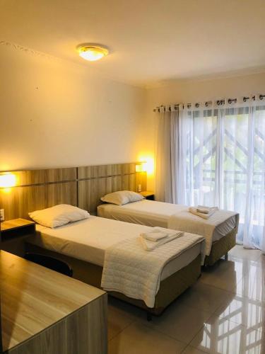 a hotel room with two beds and a window at Hotel Quinta da Bica D'Água in Florianópolis