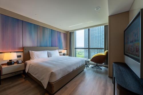 a hotel room with a bed and a flat screen tv at Holiday Inn Changchun High Tech Zone by IHG in Changchun