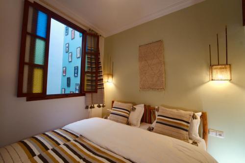 a bedroom with a bed with pillows and a window at hostel riad maqam in Essaouira