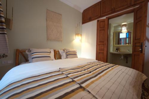 a bedroom with a large bed with striped blankets at hostel riad maqam in Essaouira